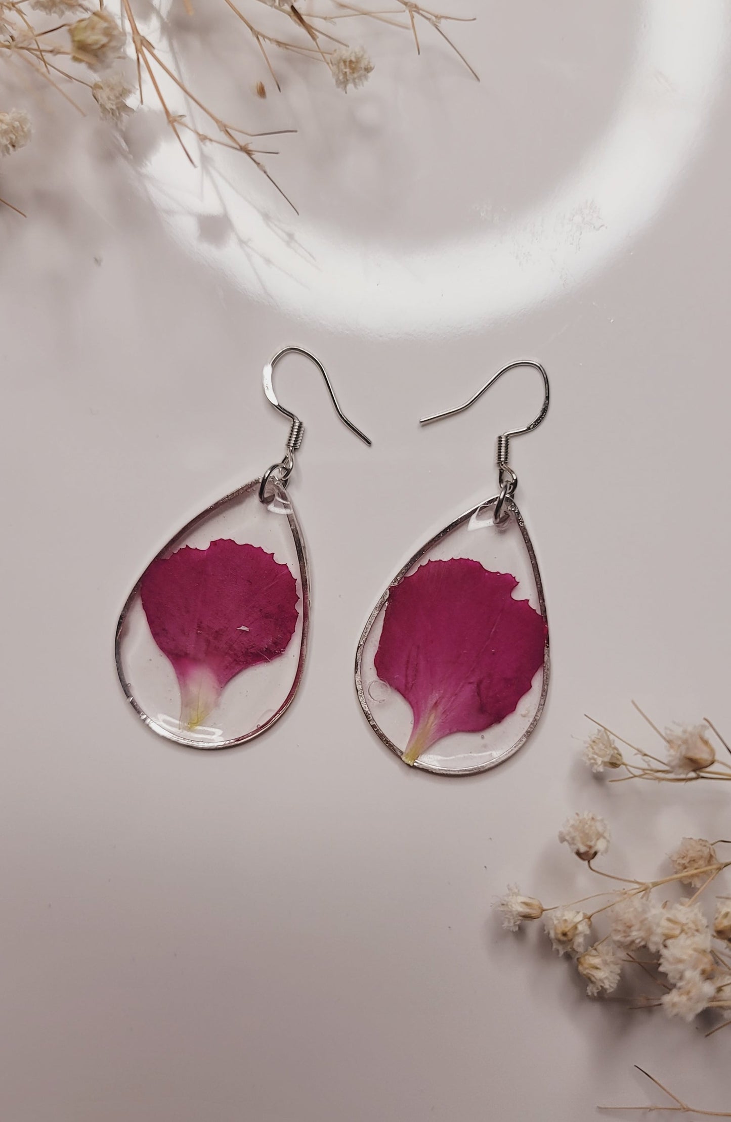 Pair of earrings with pink floral petals on a light background