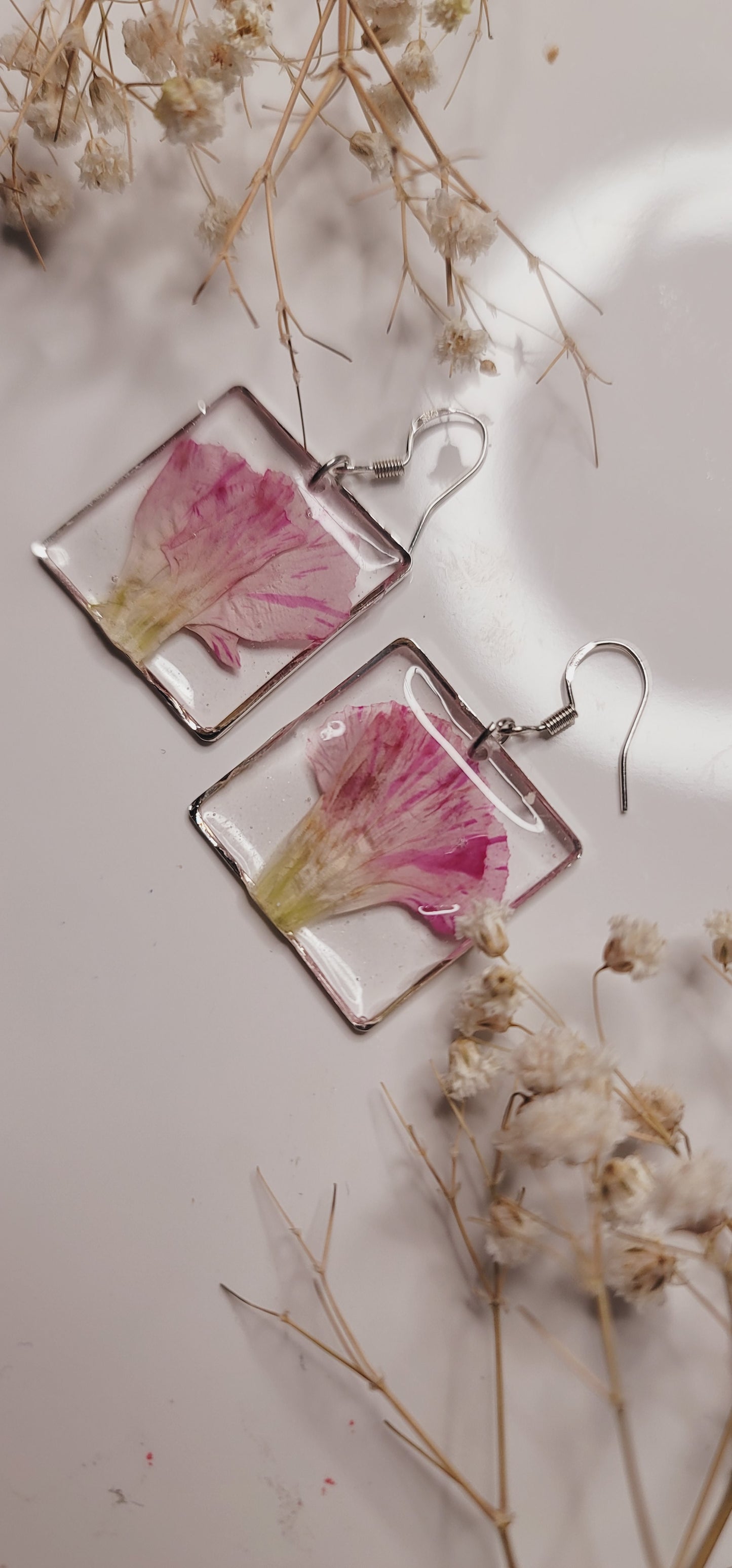 Square earrings with floral design on a light background