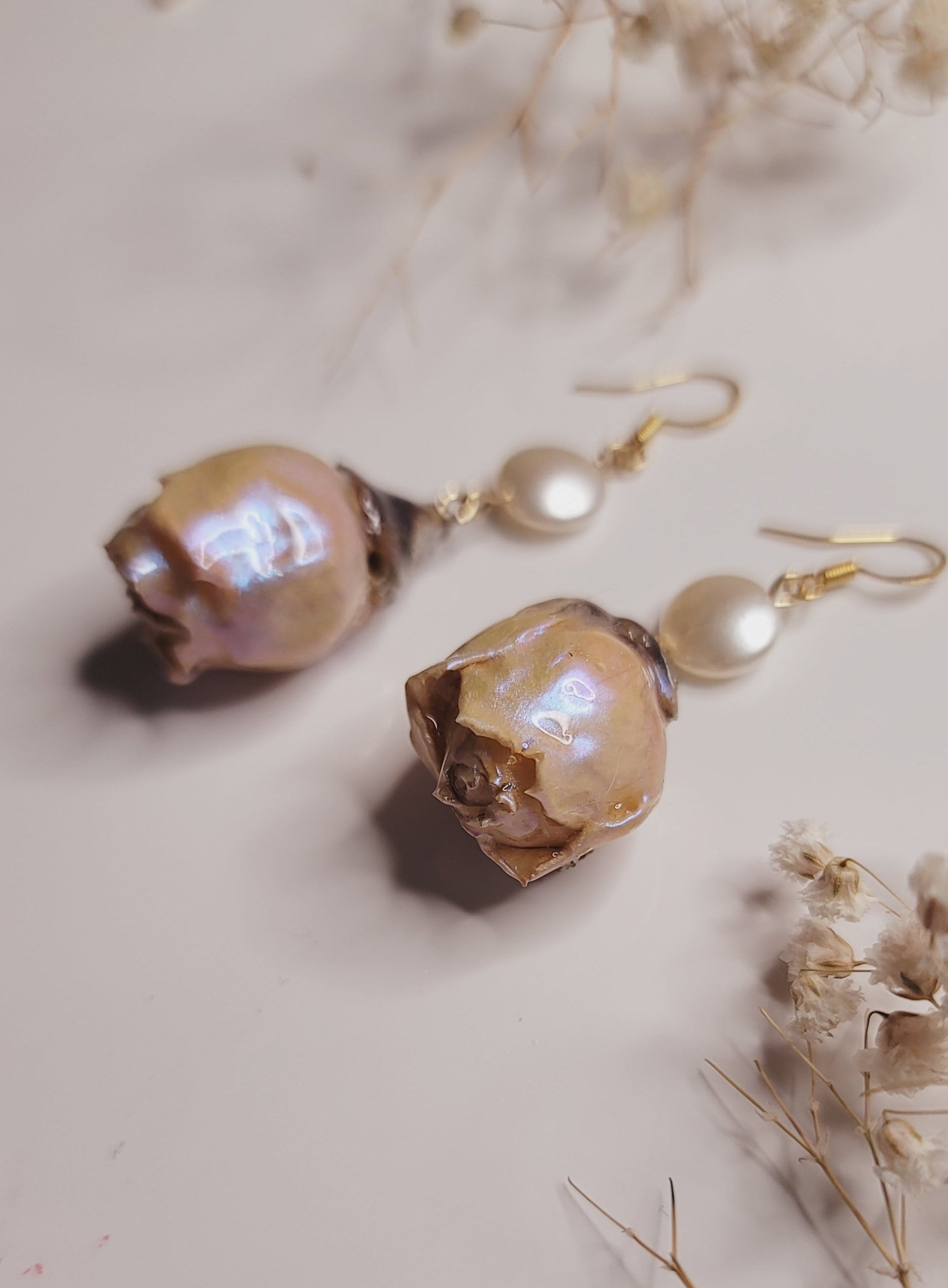 Pair of earrings with large beads and pearls on a neutral background