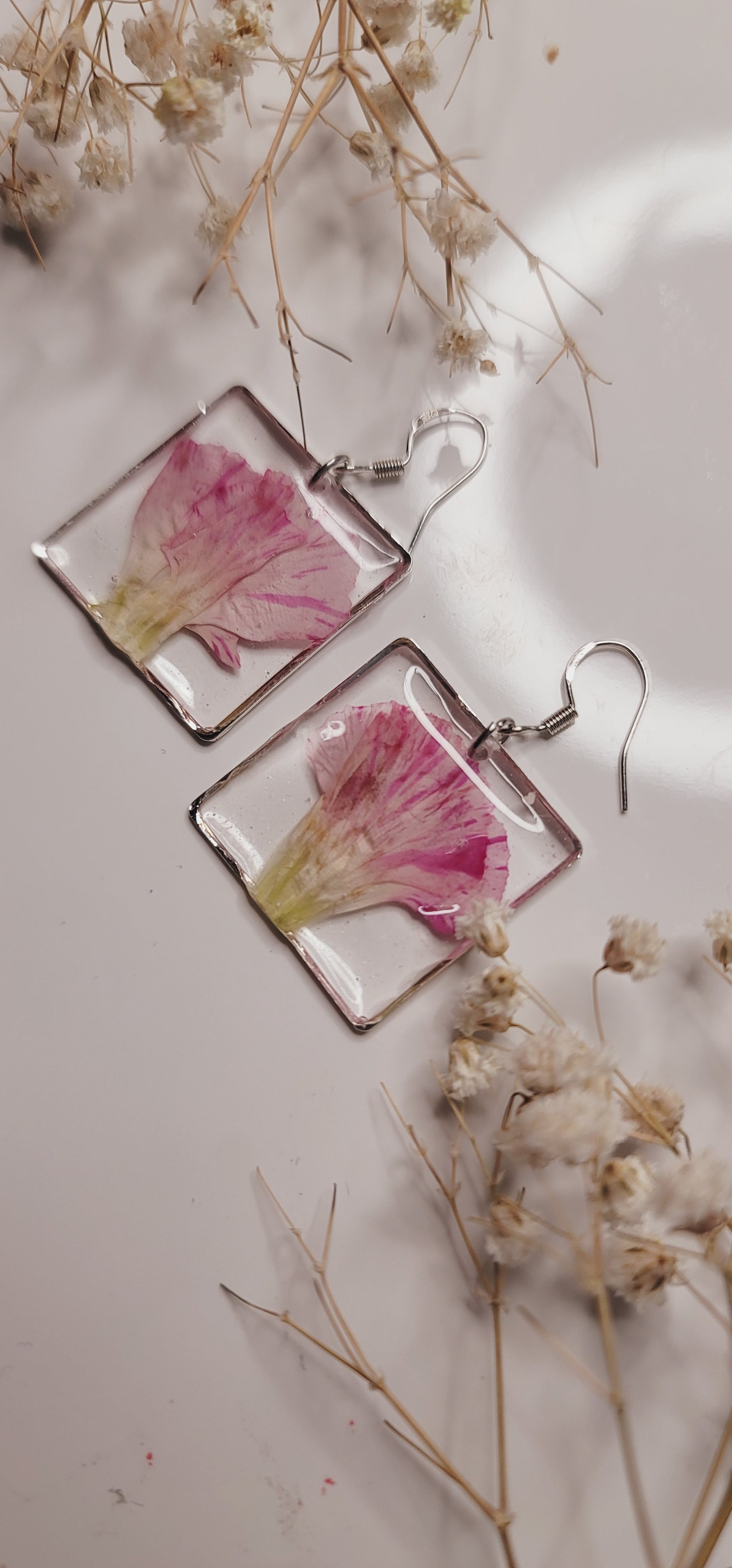Square earrings with floral design on a light background