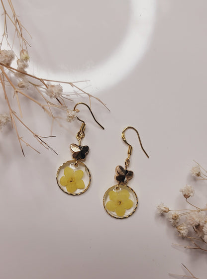 Floral earrings on a light background with dried flowers.