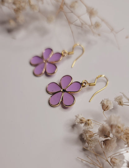 Purple flower-shaped earrings on a light background with dried flowers.