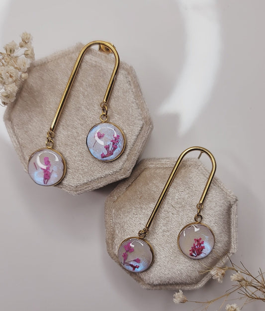 Gold brooches with floral designs on beige stones against a neutral background