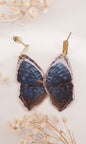 Butterfly-shaped earrings with dried flowers on a light background